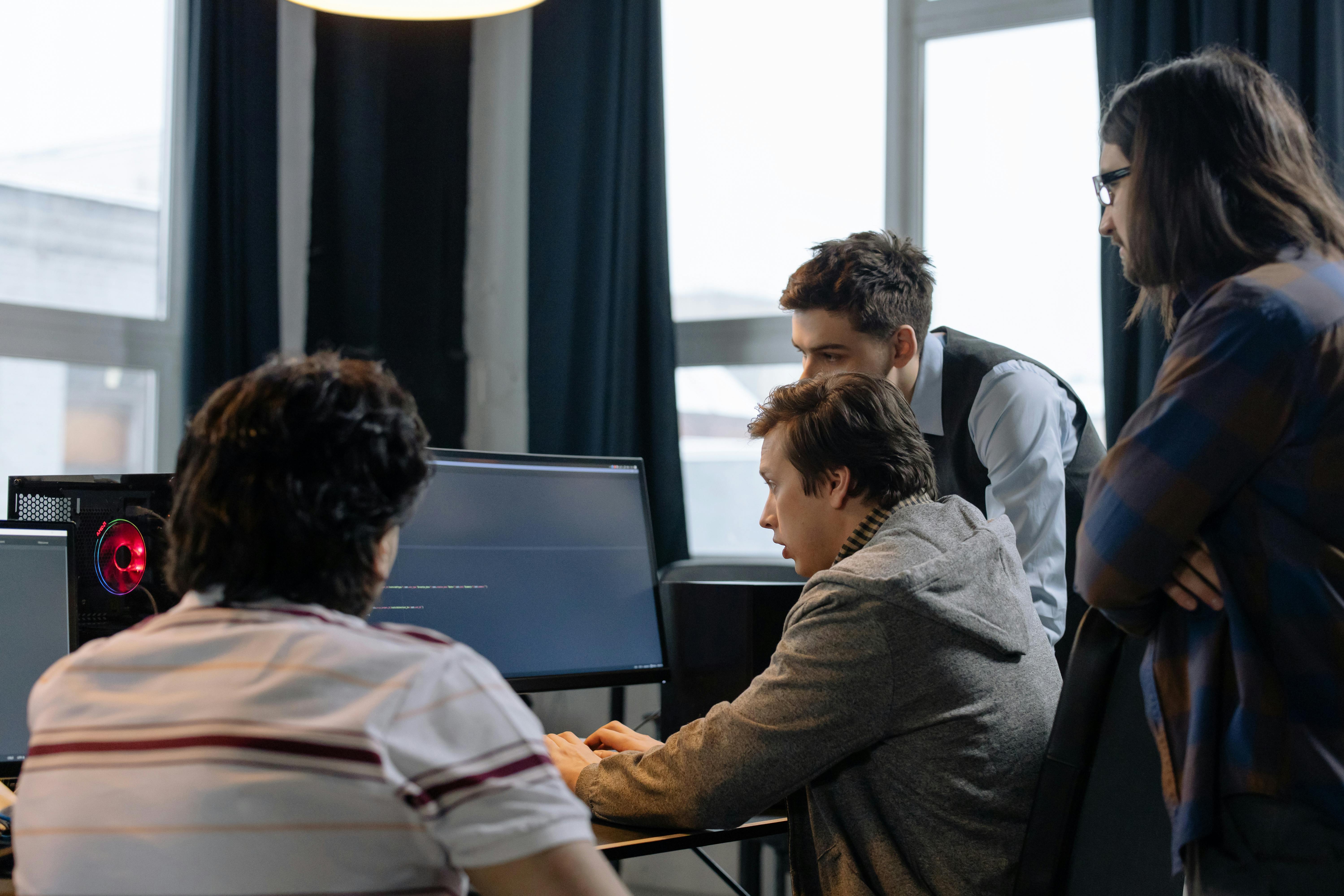 Software team collaborating around desktop monitors